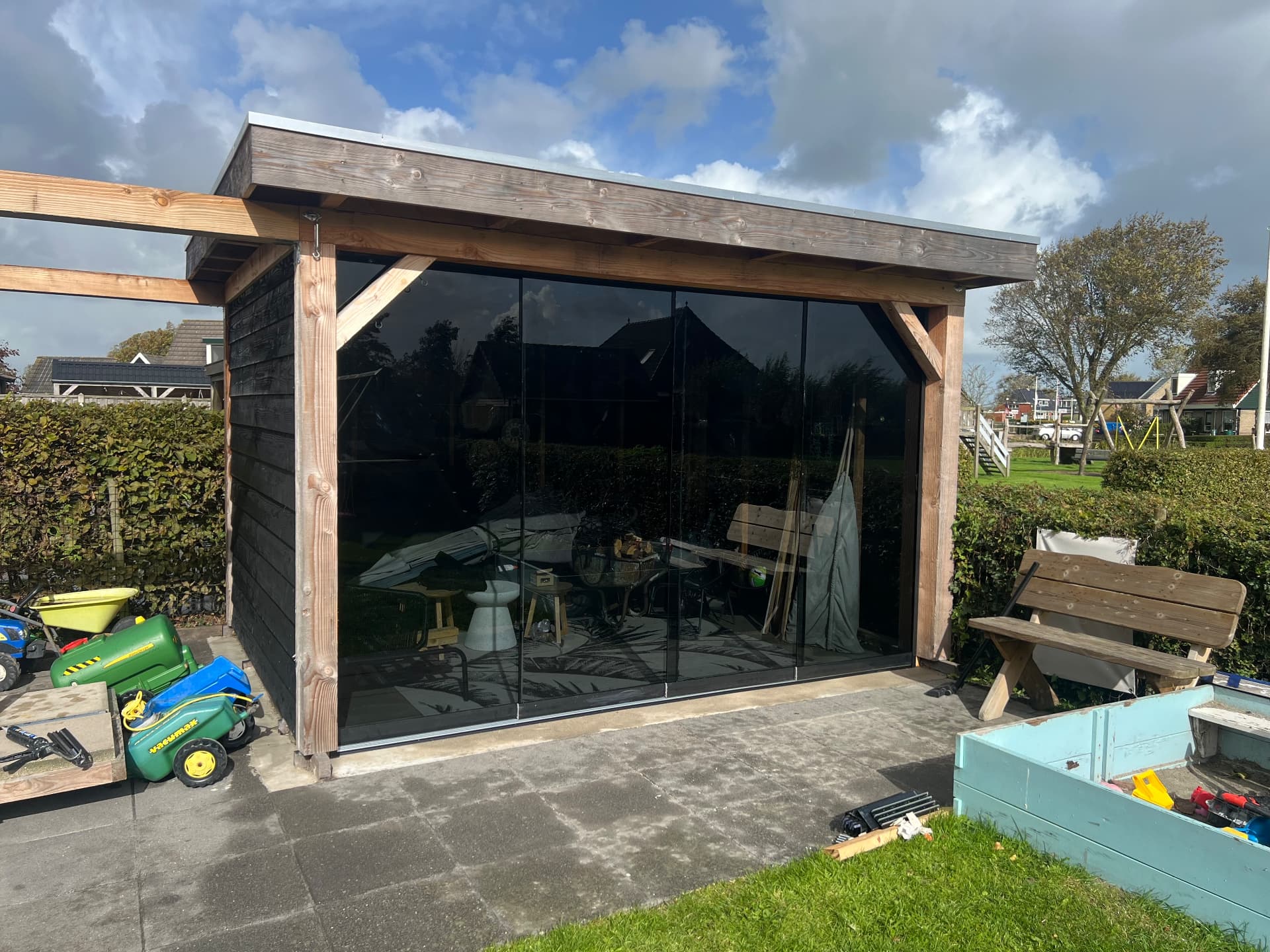 Glazen schuifwand in donker glas bij een vrijstaand tuinhuis